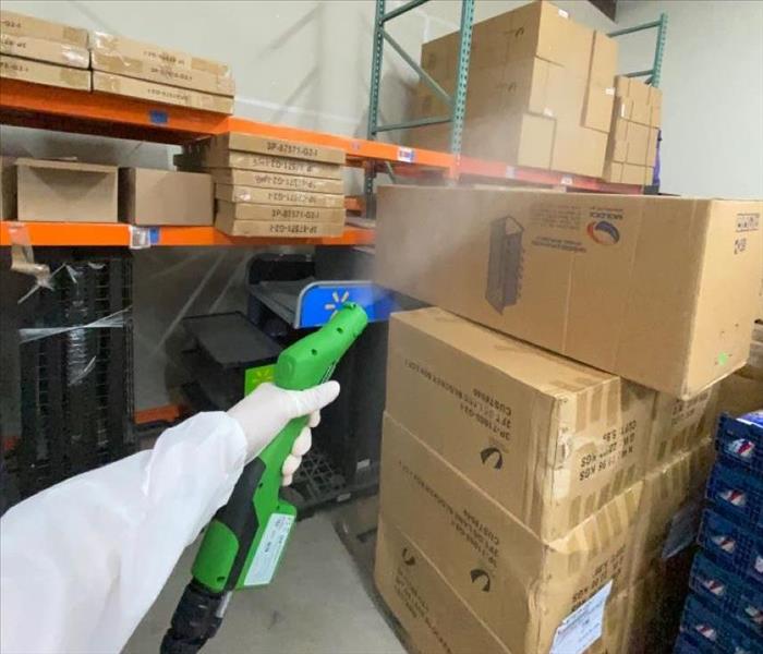 man in PPE spraying building with green sprayer 