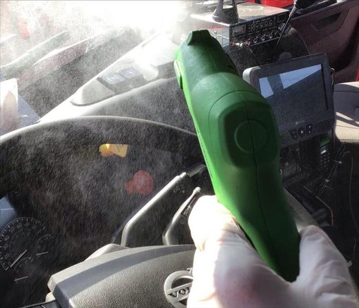 male hand holding SERVPRO sprayer with spray coming out into truck