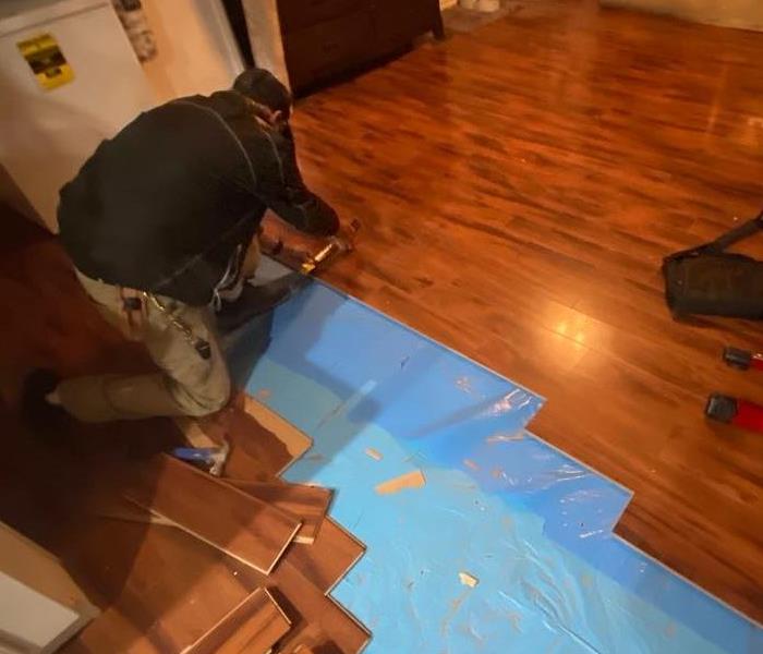 male SERVPRO employee removing hardwood from floor