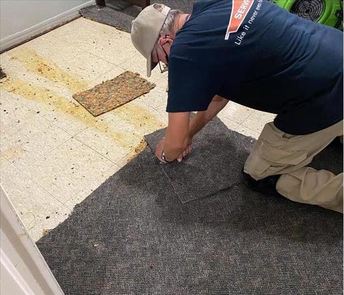 Man ripping up carpet that was water damaged 