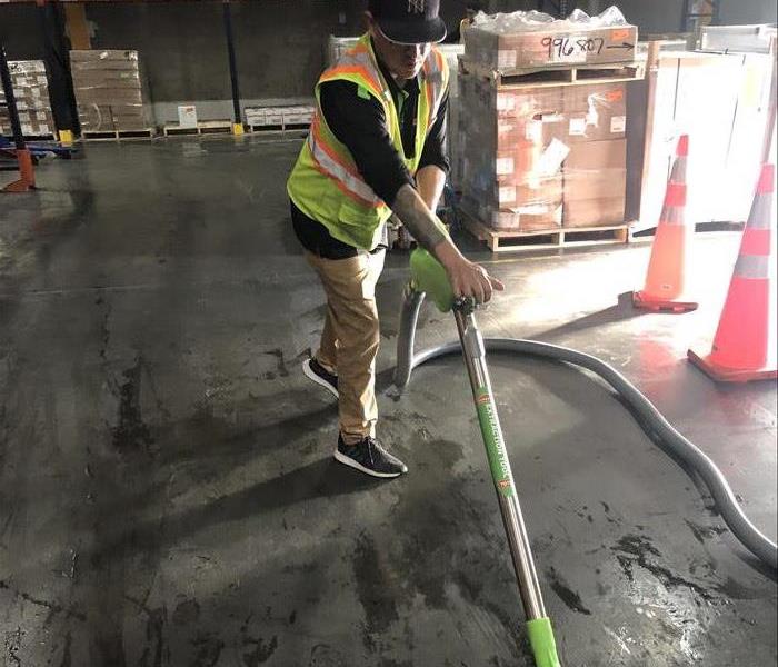 Male employee extracting water from a warehouse floor