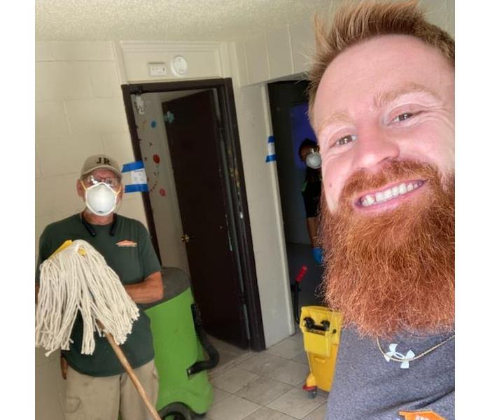 two male SERVPRO employees cleaning home after storm damage